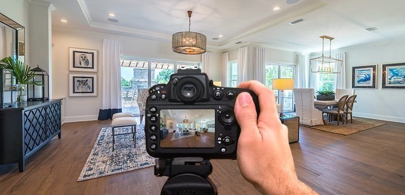 A property photographer framing a bright living room through a camera